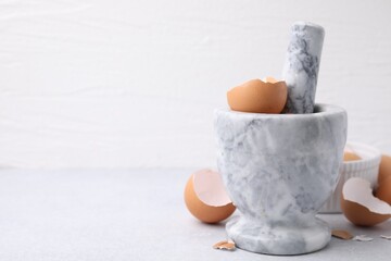 Wall Mural - Broken eggshells, mortar and pestle on grey table, closeup. Space for text