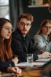 © Alexander Chaykin - Group of people seated at a wooden table with laptops and notes, suitable for business or team meeting scenario