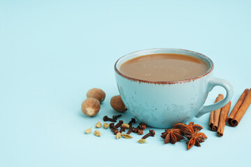 Wall Mural - Cup of tasty masala tea with different spices on blue background