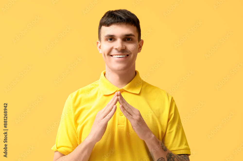 Young deaf mute man using sign language on yellow background