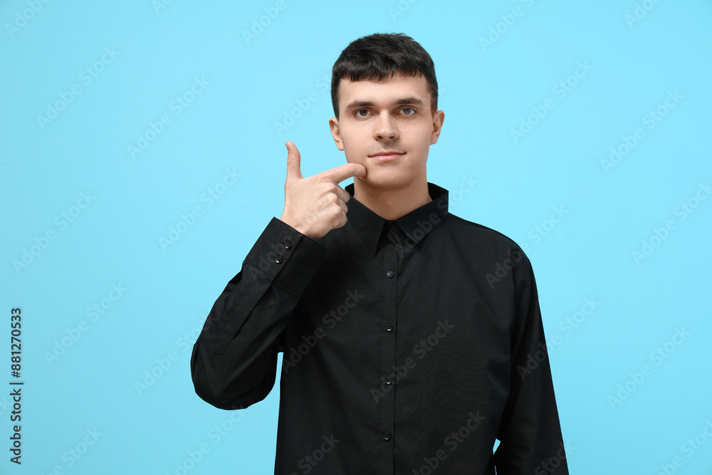 Young deaf mute man using sign language on blue background