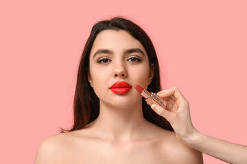 Poster - Female makeup artist working with young woman on pink background