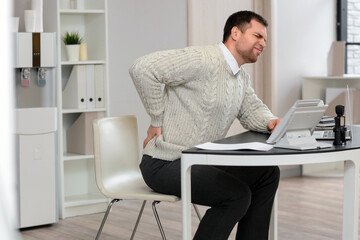 Wall Mural - Young businessman suffering from back pain at table in office