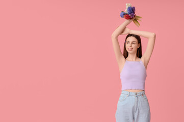 Wall Mural - Happy smiling young woman with hyacinth flowers on pink background