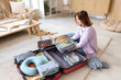 © Pixel-Shot - Young woman packing suitcase at home. Travel concept