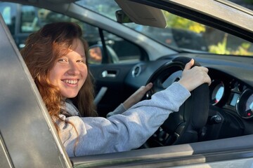 Wall Mural - young wooman or teenage girl sit behind the wheel of her own car, positive and happy