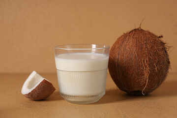 Wall Mural - Glass of tasty fresh coconut milk on beige background, closeup