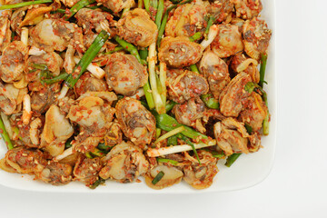 close-up of kkomag-muchim(seasoned cockles) with chives and chili powder on piece dish and white flo