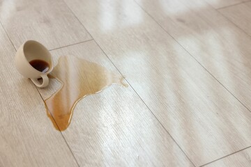 Sticker - Cup with spilled drink on wooden floor. Space for text