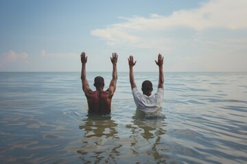 Wall Mural - Baptism. Two men are in the sea. They raise their arms up.