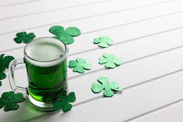 Poster - Image of glass with green beer, clover and copy space on white wooden background