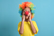 © Mulad Images - Cute little asian boy with clown wig and clown nose, surprised pose isolated on blue background. copy space