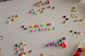 friends forever written with colorful beads. jewelry making supplies on the table. making friendship