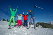 © Sergey Novikov - Colorfully dressed family of four skiing together on sunny day
