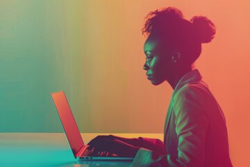 Wall Mural - A side view of an African American businesswoman seated at a desk, typing on a laptop in front of a vibrant green and orange gradient backdrop