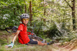 © Sergey Novikov - Mountain biker teenager rests on grassy hill after intense ride