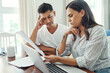 © peopleimages.com - Laptop, documents and confused couple in home for budget problem, mortgage debt and financial risk. Computer, man and woman with stress for tax paperwork, low credit score and inflation for expenses