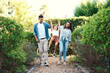 © CanBorg/peopleimages.com - Girl, parents and swinging on walk in garden, support and child fun on countryside holiday. Family, daughter and holding hands together in park of nature, playing and vacation for love relationship