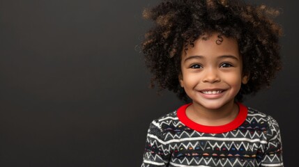 Wall Mural - A young boy with curly hair smiles brightly at the camera