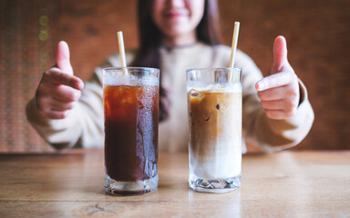 Wall Mural - Closeup image of a young woman pointing finger at two glasses of iced coffee