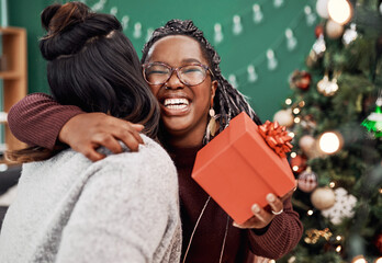 Women, hug and gift with Christmas tree for festive, holiday and celebration as happy friends in home. Female people, together and love with presents, excited and gratitude for bonding in December