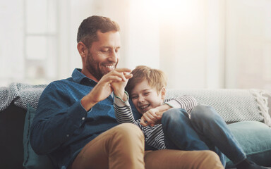 Canvas Print - Father, boy and laughing on sofa together in home, bonding and hug for funny conversation. Daddy, son and happy family playing in living room for joke, talk and embrace for security in relationship