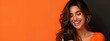 © Arma - Photo of an elegant young woman in her 20s with long wavy hair, happy smiling while using a mobile phone on an orange and black background with copy space.