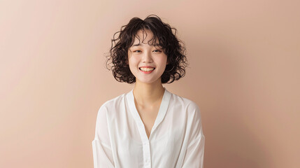 A cheerful woman with curly hair, smiling against a soft pink background, highlighting positivity, joy, and a friendly demeanor.