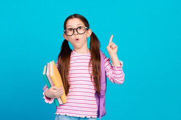 Poster - Photo of impressed girl dressed striped shirt in glasses holding book directing at sale empty space isolated on blue color background