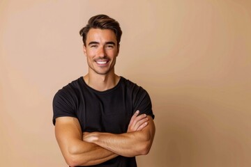 Wall Mural - Handsome Man Smiling. Caucasian Male Model with Crossed Arms in Frontal Pose on Beige Studio Background