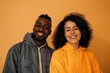 © CogniLens - Portrait of a satisfied multiethnic couple in their 30s wearing a zip-up fleece hoodie while standing against soft orange background
