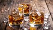 © AkuAku - Whiskey served with ice in glasses on a rustic wooden backdrop
