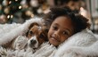 © Olga - A little African-American girl and a puppy are warming up under a cozy white blanket. Cute Christmas New Year card. New Year's Christmas atmosphere. Close-up.