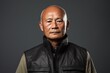 © Markus Schröder - Portrait of a content asian man in his 60s dressed in a water-resistant gilet isolated in plain cyclorama studio wall