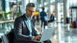 © Dani Liso - Focused Businessman Typing on Laptop in Busy Modern Airport Lounge