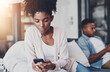 © peopleimages.com - Phone, ignore and black couple on sofa in home for tension in argument, fight and communication. Dating, relationship and man and woman on smartphone for social media, internet and bored together