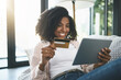 © peopleimages.com - Woman, card and tablet and happy on couch, fintech and transaction for online shopping in home. Customer, internet payment and credit score app or banking, ecommerce and smile or purchase on sofa