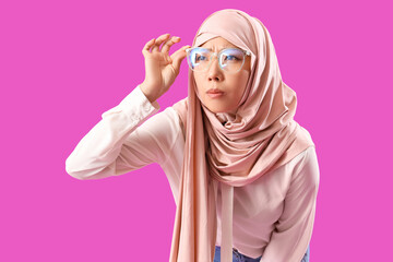 Sticker - Beautiful young Asian woman in hijab and eyeglasses on purple background