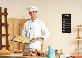 Canvas Print - Handsome young chef with tray of fresh raw buns in bakery