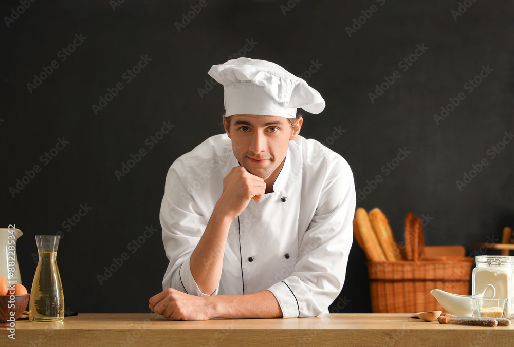 Handsome young chef with ingredients on black background