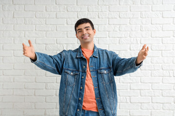 Wall Mural - Young man opening arms for hug on white brick background