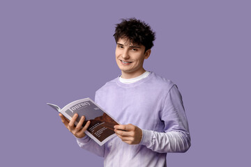 Wall Mural - Handsome young man in stylish sweatshirt with magazine on purple background