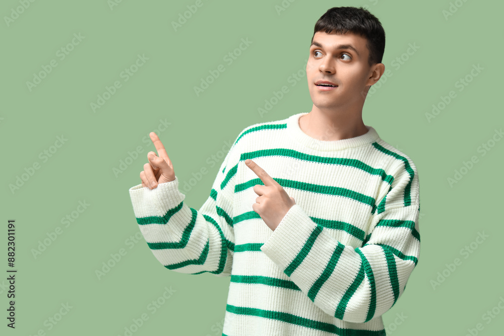Young deaf mute man using sign language on green background