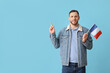 © Pixel-Shot - Young man with flag of France pointing at something on blue background