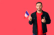 © Pixel-Shot - Young man with flag of France showing thumb-up on red background