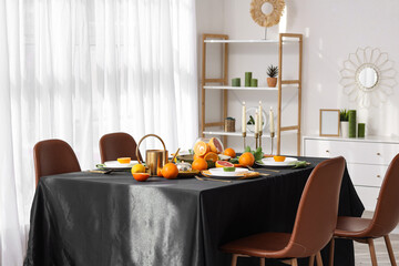 Canvas Print - Beautiful table setting with citrus fruits, burning candles and black tablecloth in living room