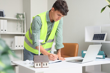 Sticker - Male engineer with wind turbine and house model working at table in office