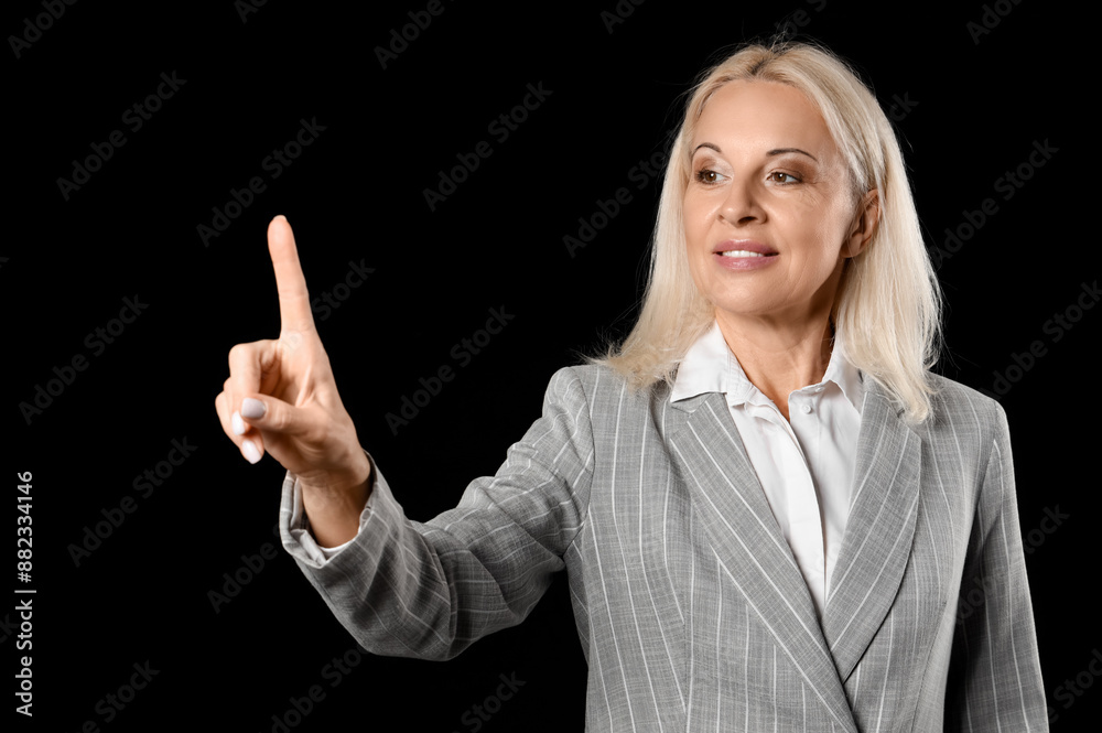 Mature businesswoman using virtual screen on black background