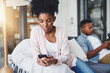 © peopleimages.com - Phone, ignore and black couple on sofa in home for tension in argument, conflict and communication. Dating, relationship and man and woman on smartphone for cheating, chat and social media attention