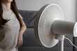 © Alina - Girl near cooling fan in summer heat. Fan on the sofa. Summer heat